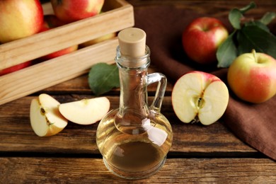 Photo of Natural apple vinegar and fresh fruits on wooden table