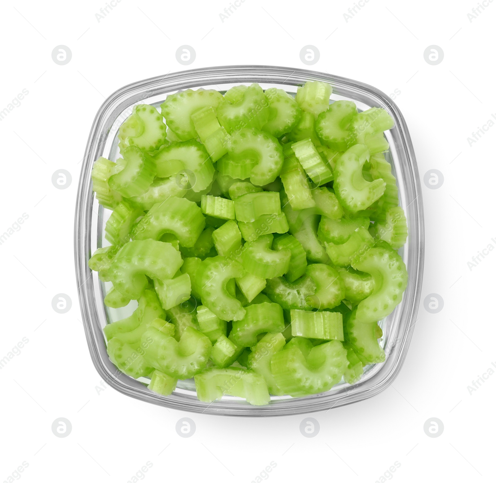 Photo of Glass bowl of fresh cut celery isolated on white, top view