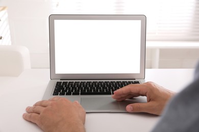 Photo of Man with modern laptop at white table indoors, closeup. Space for design