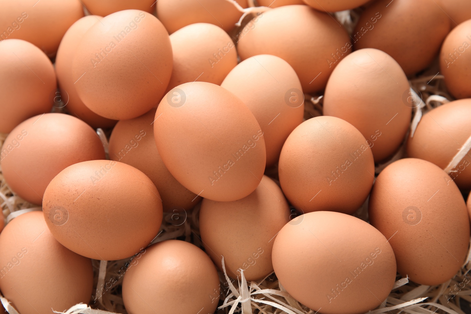 Photo of Pile of raw brown chicken eggs in straw