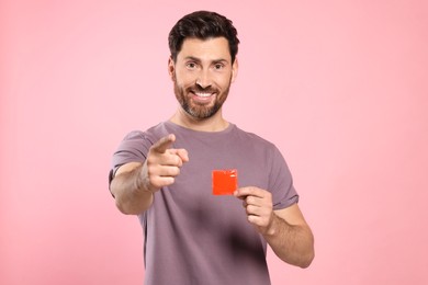 Photo of Happy man holding condom on pink background. Safe sex