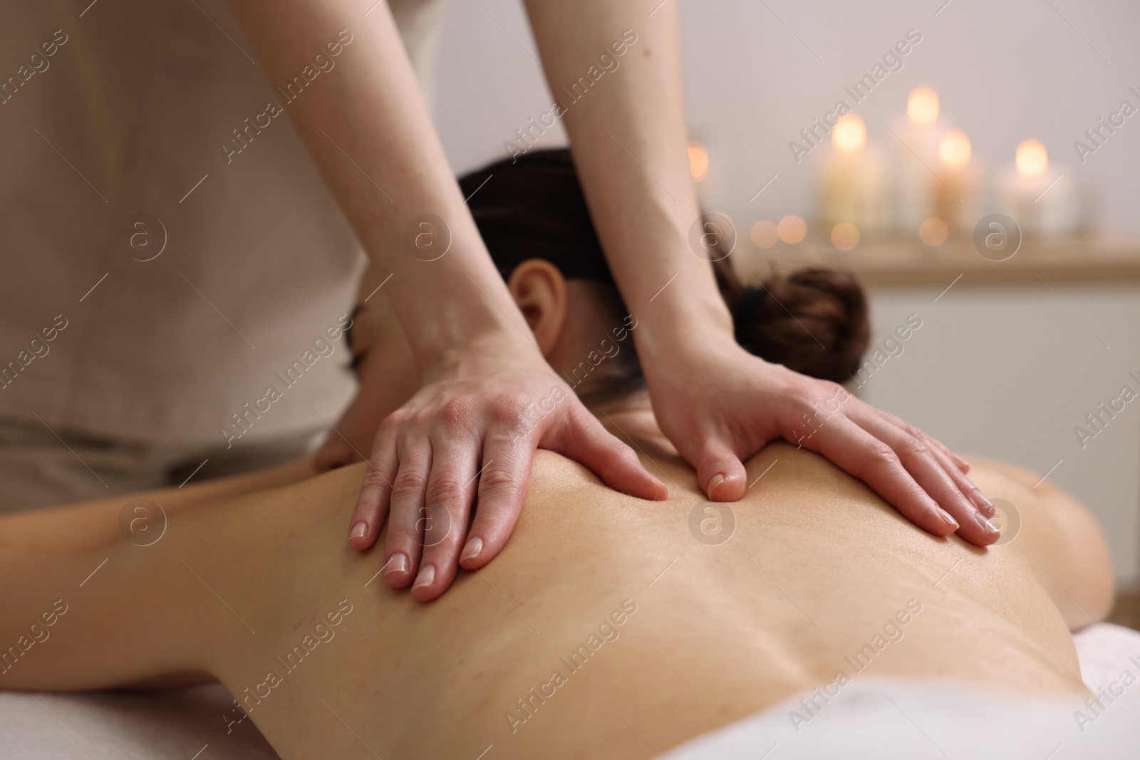 Photo of Woman receiving back massage in spa salon, focus on hands