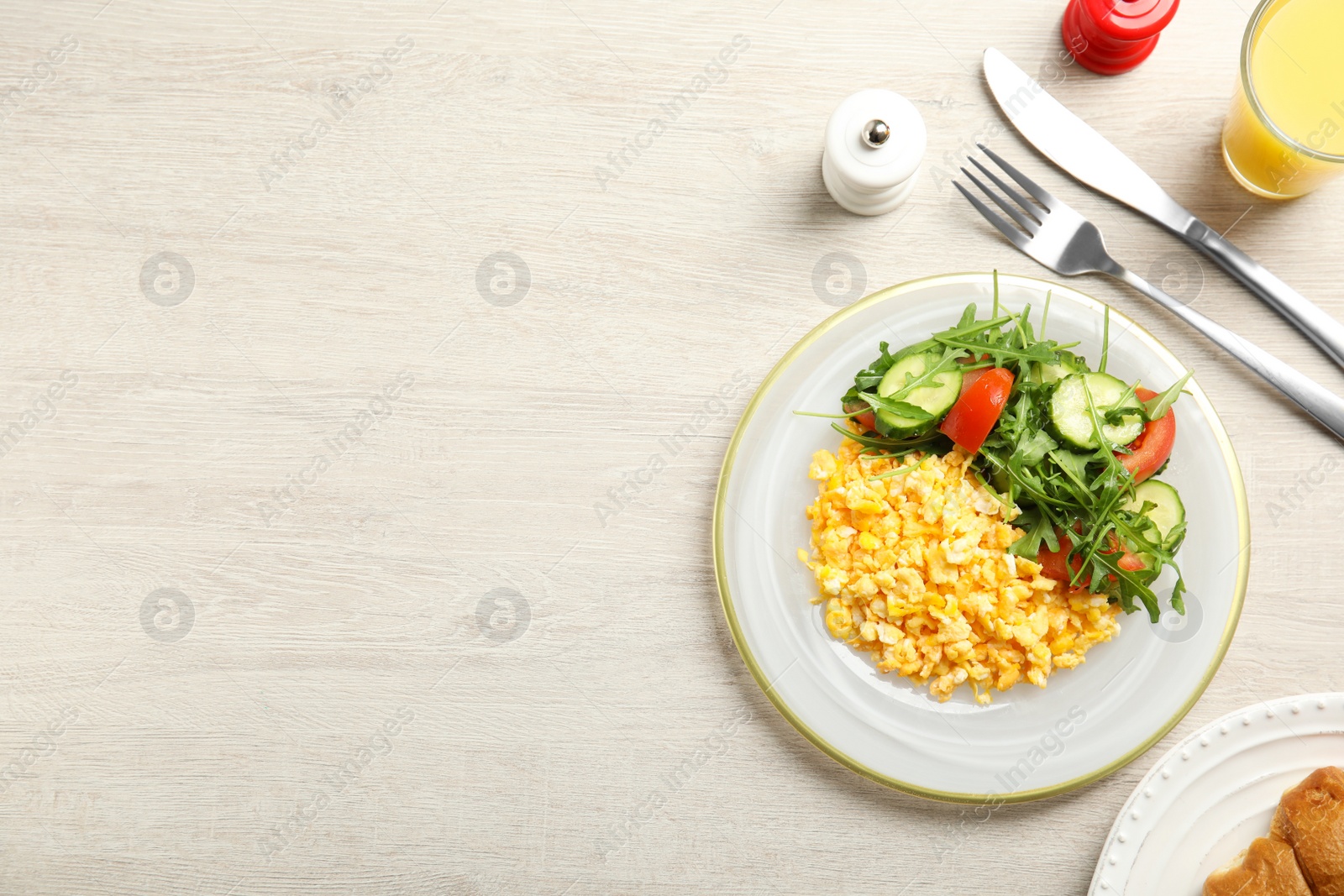 Photo of Tasty scrambled eggs with garnish served on white wooden table, flat lay. Space for text