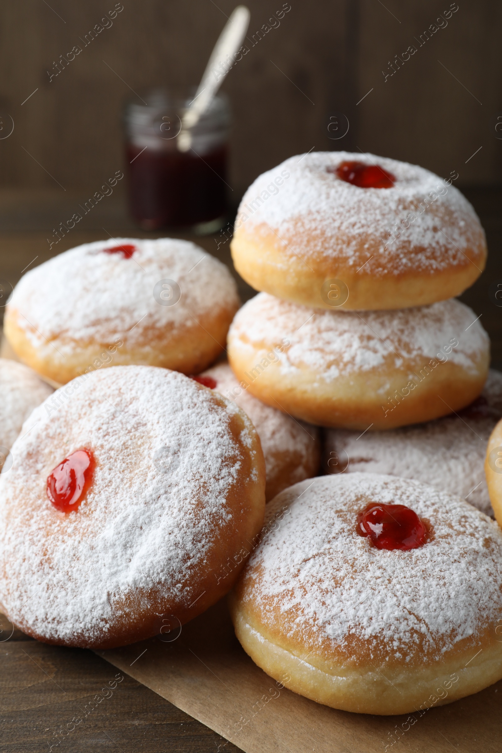 Photo of Many delicious donuts with jelly and powdered sugar on wooden table, closeup