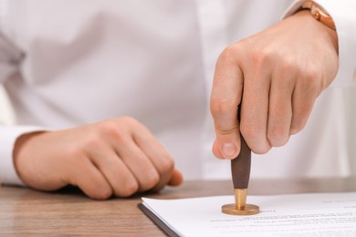 Photo of Man stamping document at wooden table, closeup