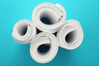 Photo of Blank white paper rolls on light blue background, flat lay