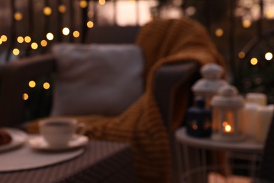 Photo of Blurred view of garden furniture with pillow, soft blanket and coffee at balcony
