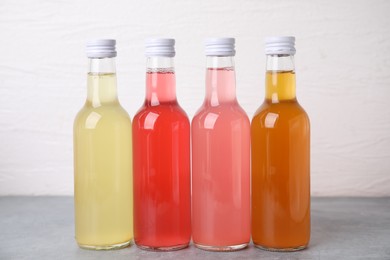 Photo of Delicious kombucha in glass bottles on grey table against white background