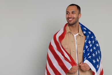 Photo of 4th of July - Independence Day of USA. Happy man with American flag on light grey background, space for text