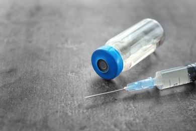 Photo of Vial with vaccine and syringe on grey background