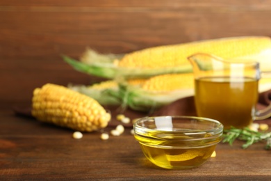 Photo of Bowl with fresh corn oil on wooden table