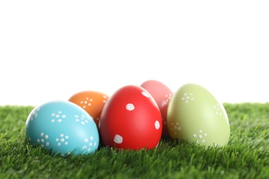 Photo of Colorful painted Easter eggs on green grass against white background