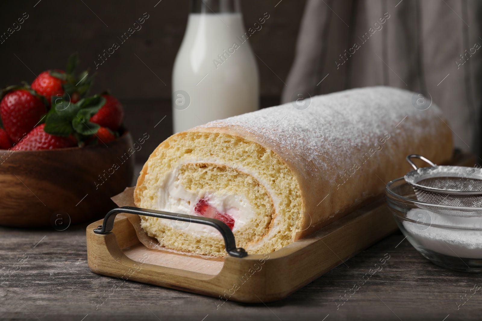 Photo of Delicious sponge cake roll with strawberries and cream on wooden table