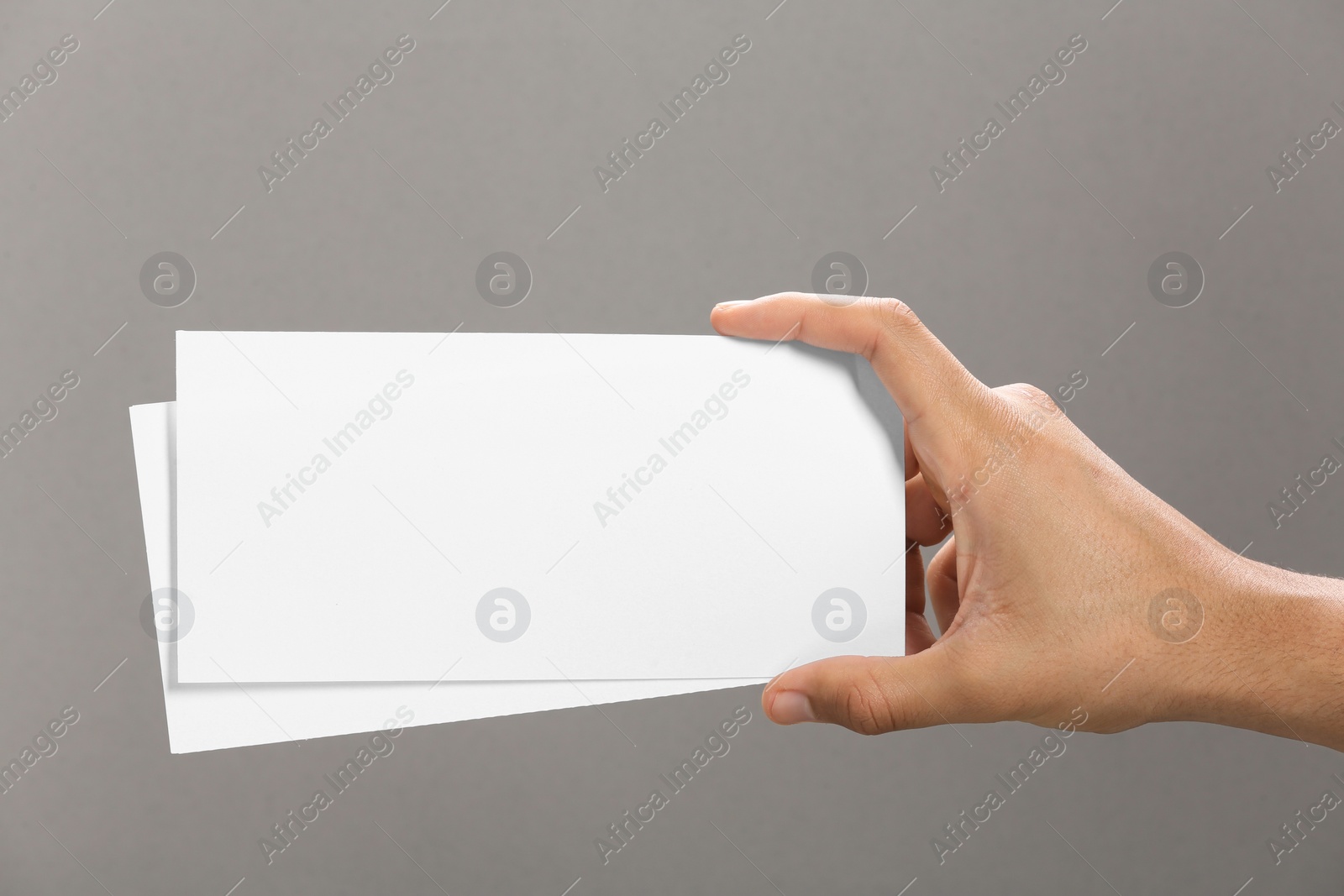 Photo of Man holding flyers on grey background, closeup. Mockup for design