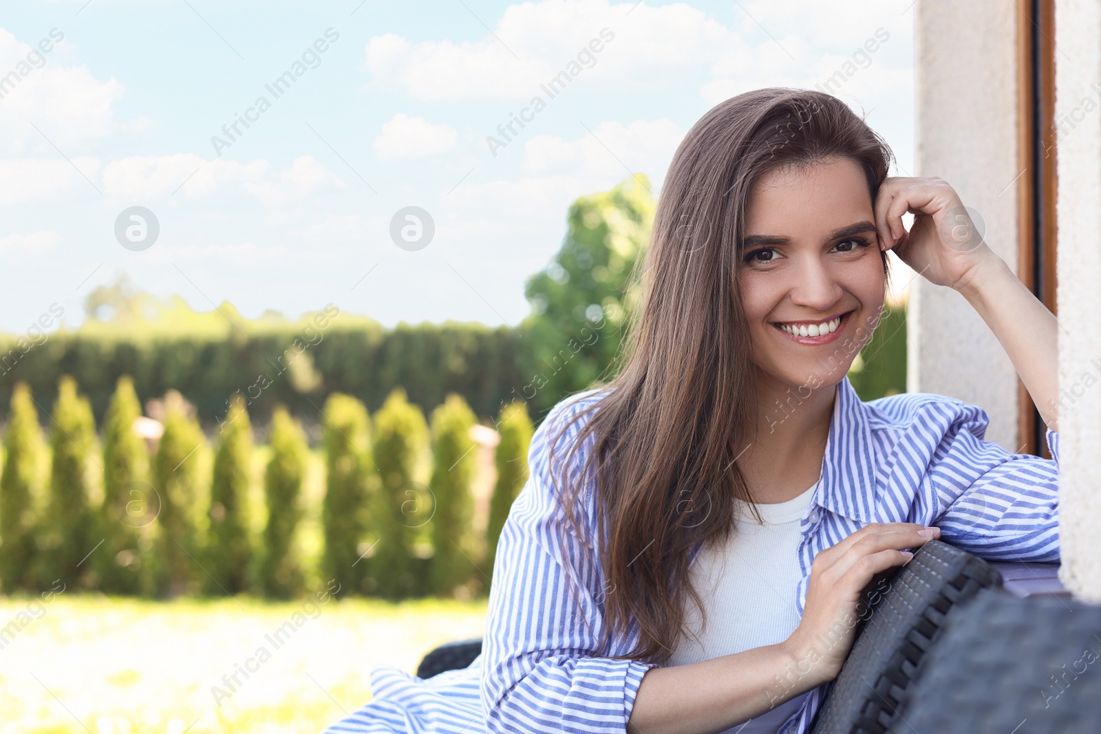 Photo of Portrait of beautiful young woman sitting on chair at backyard, space for text