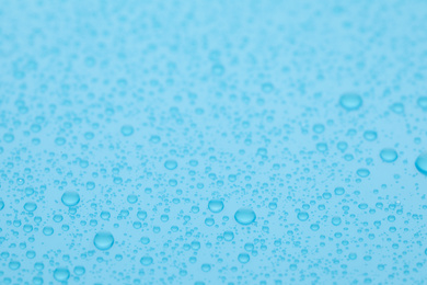 Water drops on light blue background, closeup view