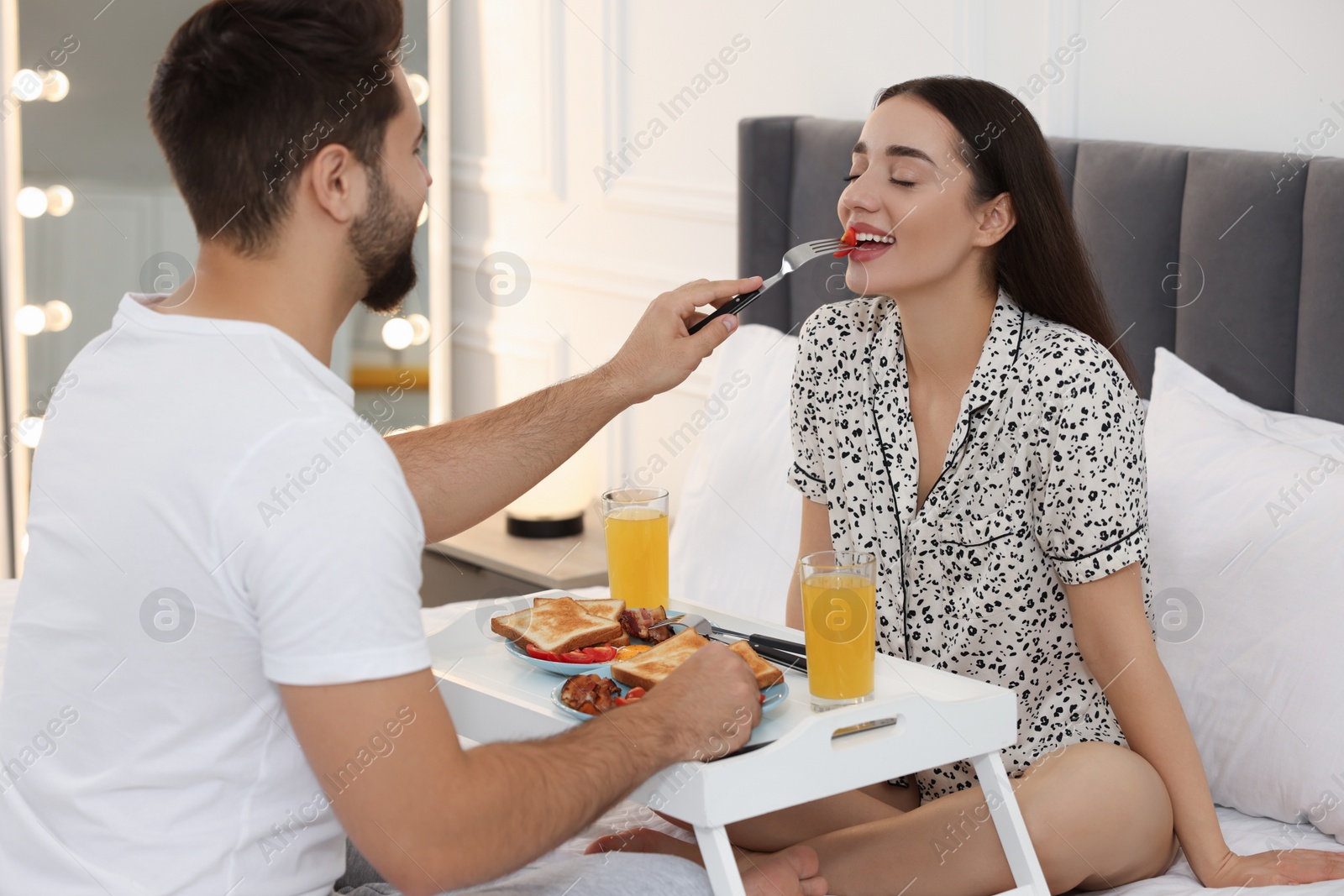 Photo of Happy couple having breakfast on bed at home