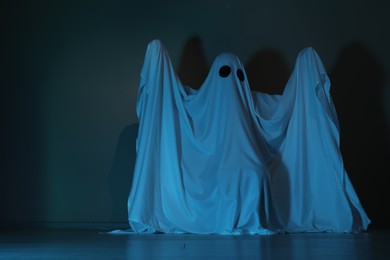 Photo of Creepy ghost. Woman covered with sheet in color light