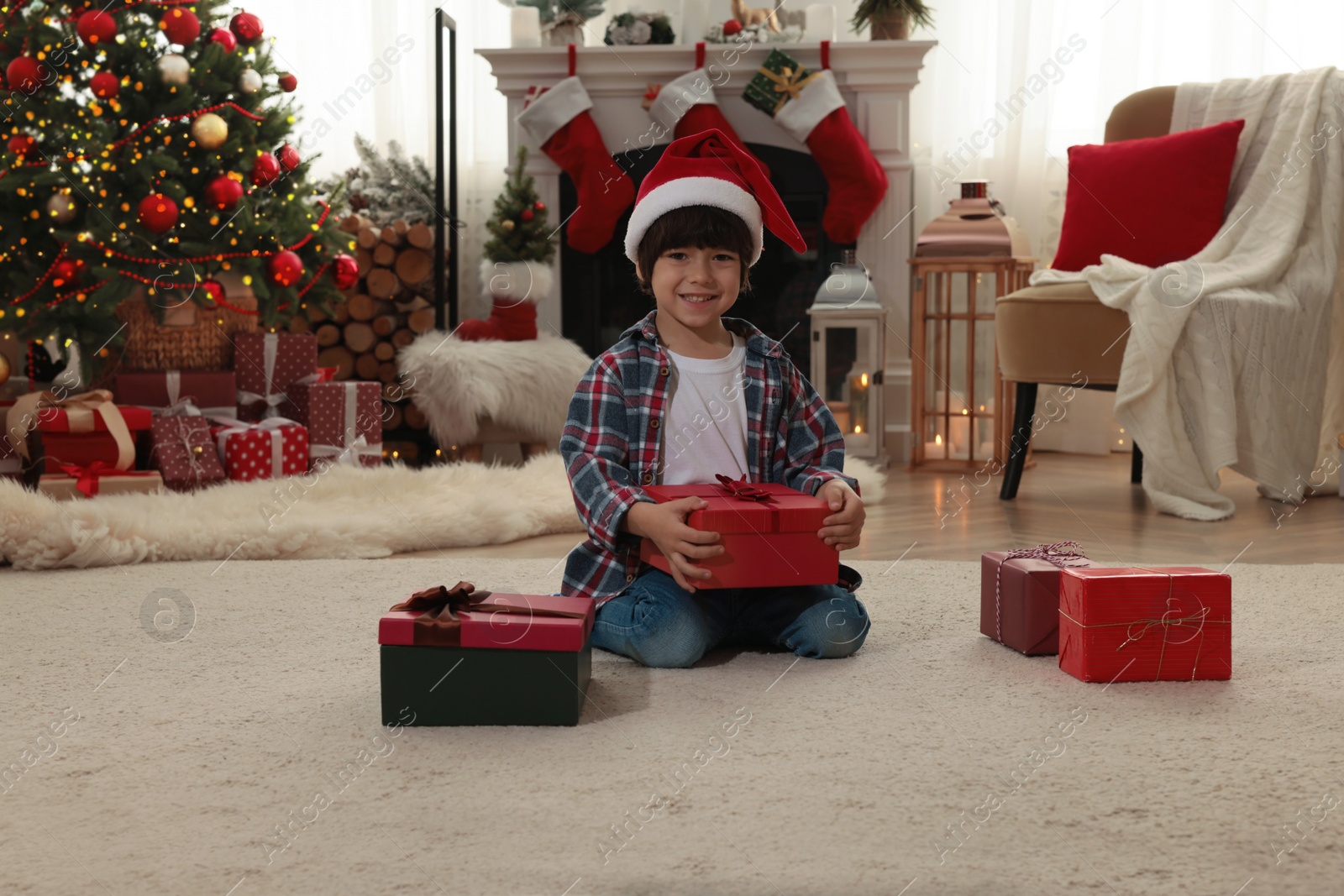 Photo of Happy child with Christmas gifts on floor at home