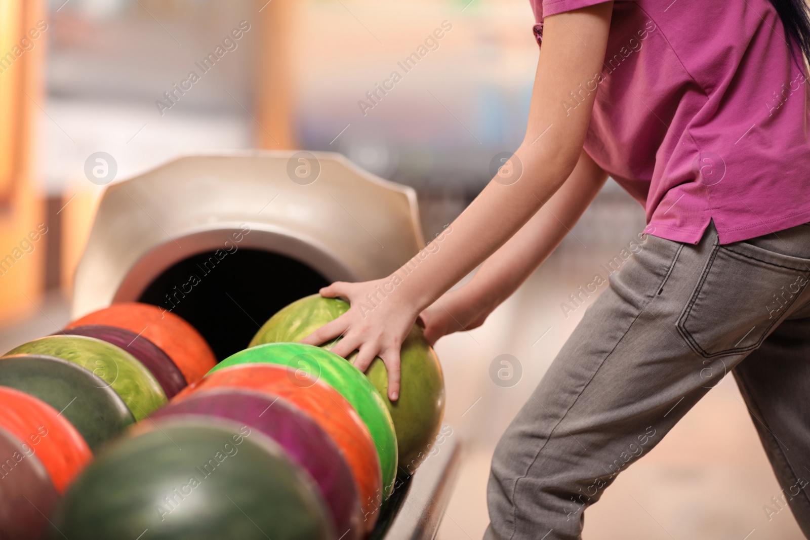 Photo of Little girl taking ball in bowling club, closeup