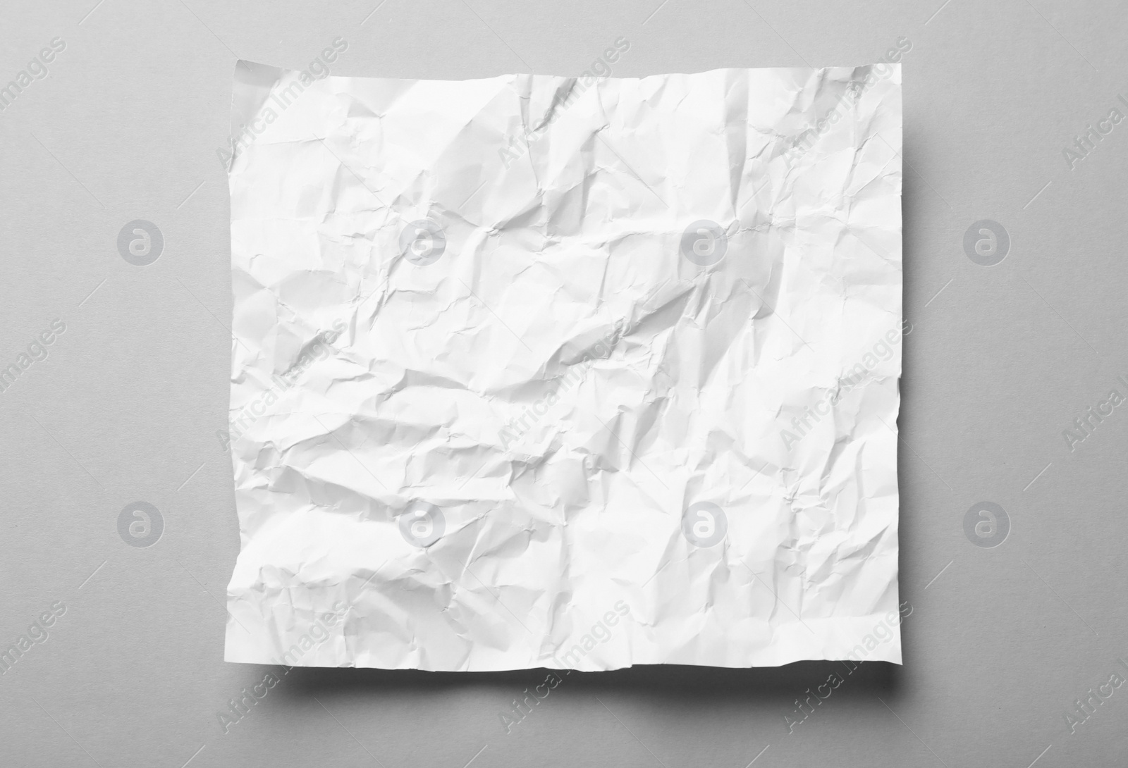 Photo of Sheet of white crumpled paper on grey background, top view