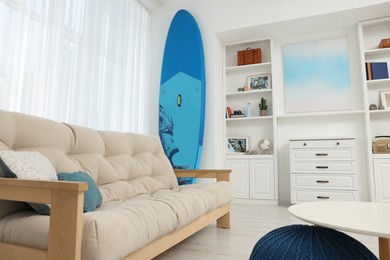 SUP board and modern furniture in stylish living room. Interior design