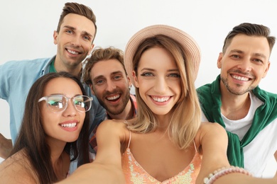 Group of happy young people taking selfie on white background