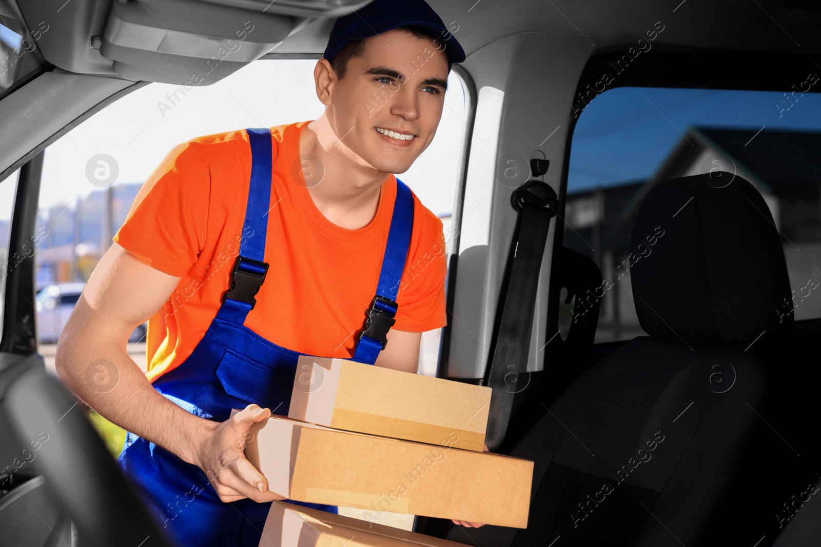 Photo of Courier taking parcels from car. Delivery service