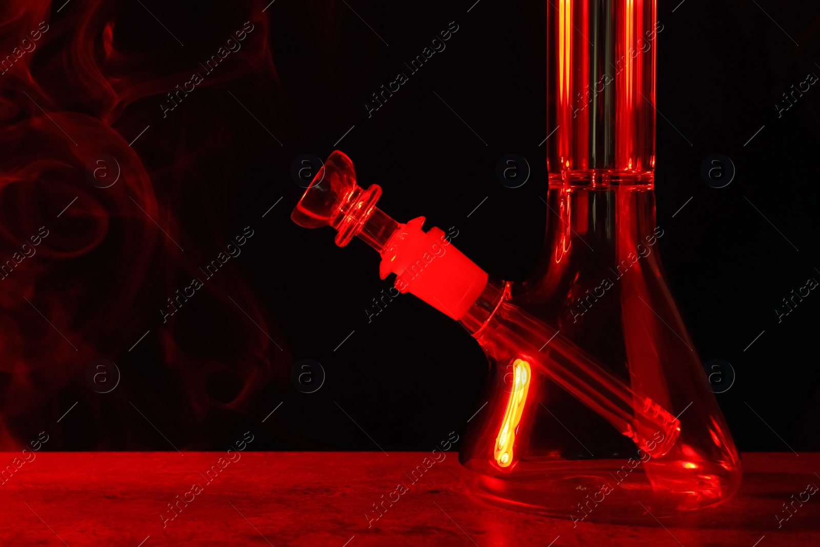Photo of Glass bong on black background, toned in red. Smoking device