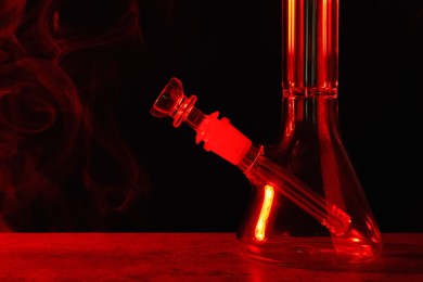Glass bong on black background, toned in red. Smoking device