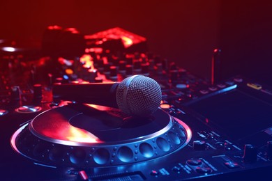 Photo of Closeup view of modern DJ controller with microphone on color background