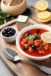 Photo of Meat solyanka soup with sausages, olives and vegetables in bowl served on grey table, closeup