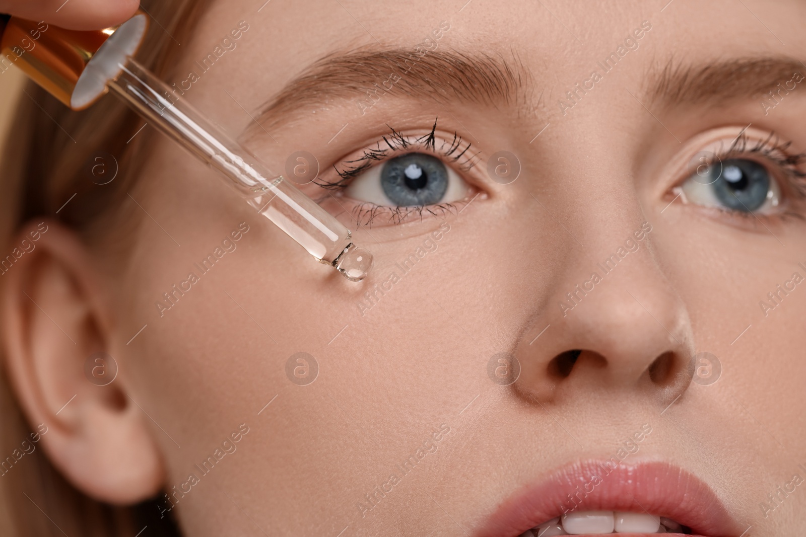 Photo of Woman applying essential oil onto face, closeup