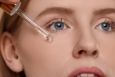 Woman applying essential oil onto face, closeup