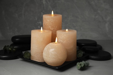 Composition with burning candles, spa stones and eucalyptus on grey table