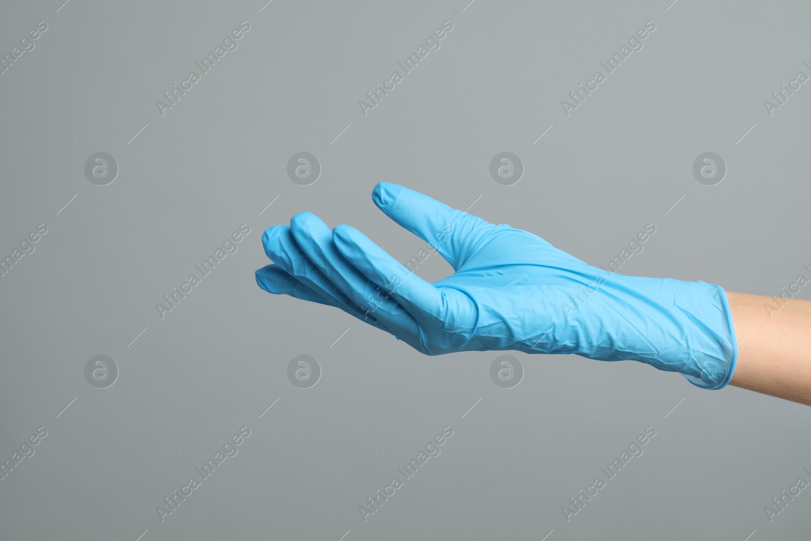 Photo of Doctor wearing medical gloves on grey background, closeup