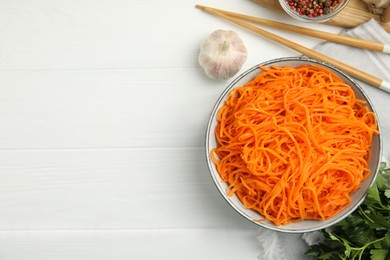 Photo of Delicious Korean carrot salad, garlic, parsley and spices on white wooden table, flat lay. Space for text