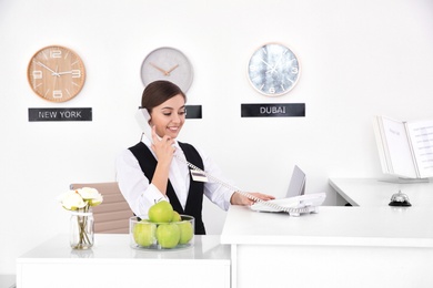 Female receptionist talking on phone at workplace in hotel