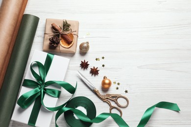 Flat lay composition with beautiful Christmas gift boxes and wrapping paper on white wooden table. Space for text
