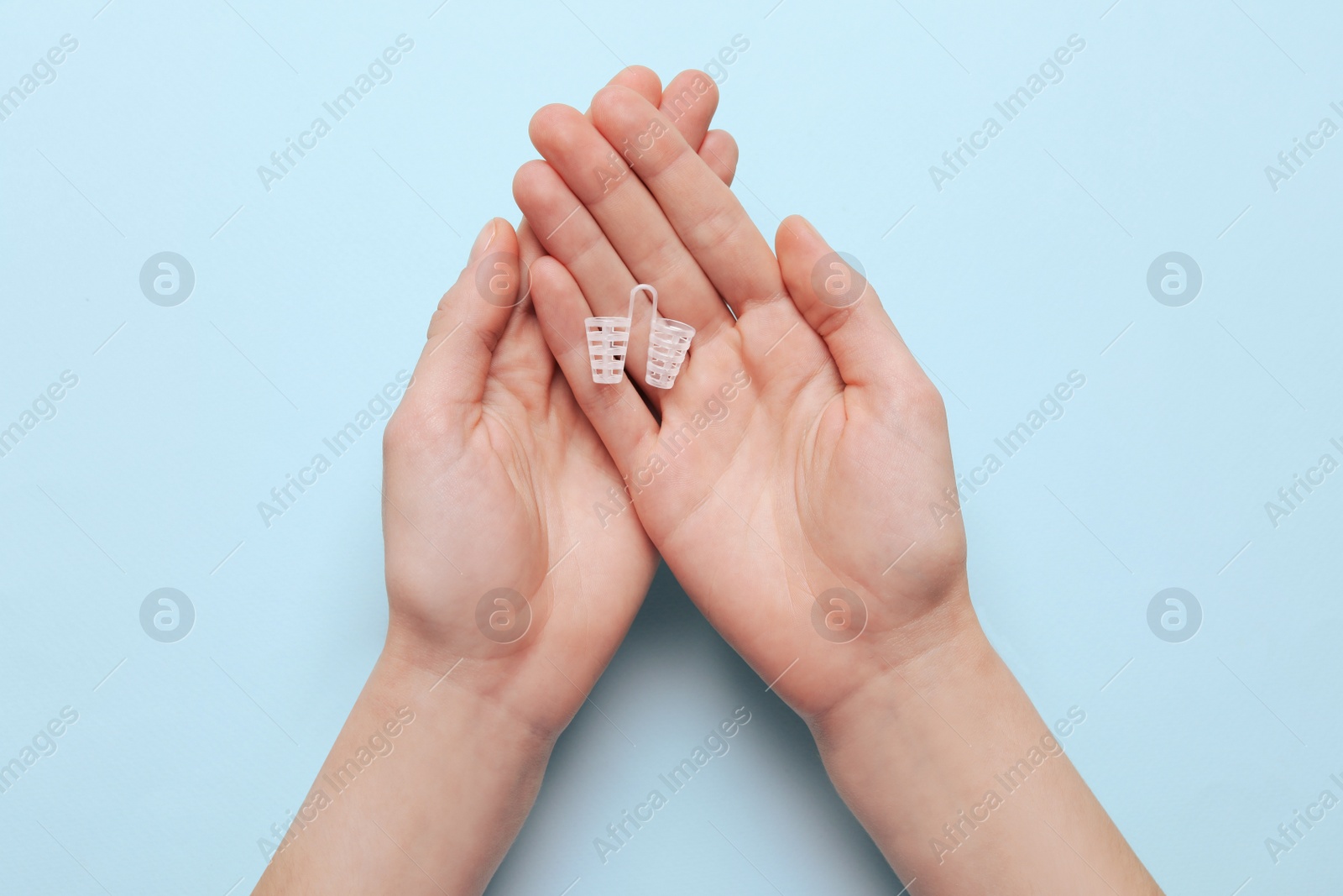 Photo of Woman holding anti-snoring device for nose on turquoise background, top view