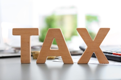 Photo of Word TAX on table against blurred background
