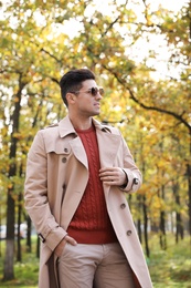 Handsome man walking in park on autumn day