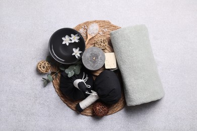 Flat lay composition with herbal massage bags, spa products and flowers on light grey table