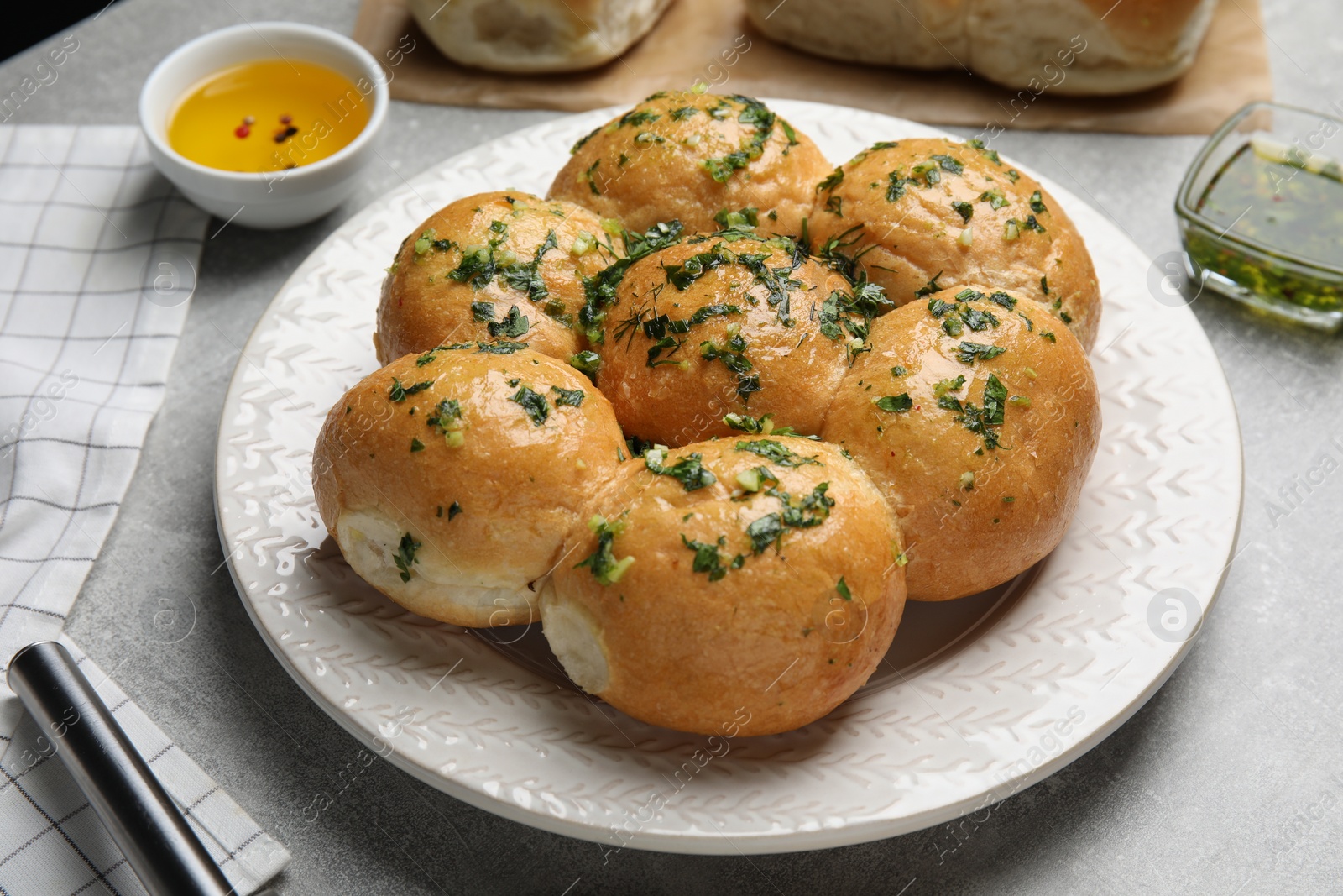 Photo of Traditional pampushka buns with garlic and herbs on grey table