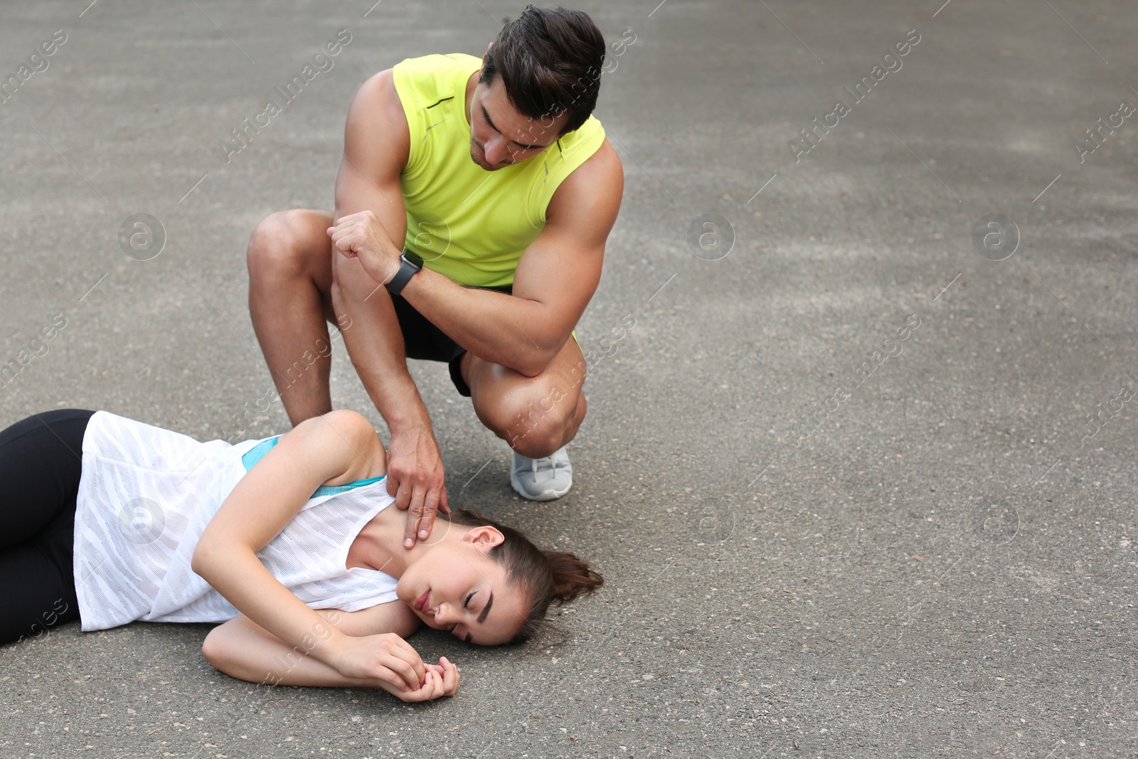 Photo of Young man checking pulse of unconscious woman on street