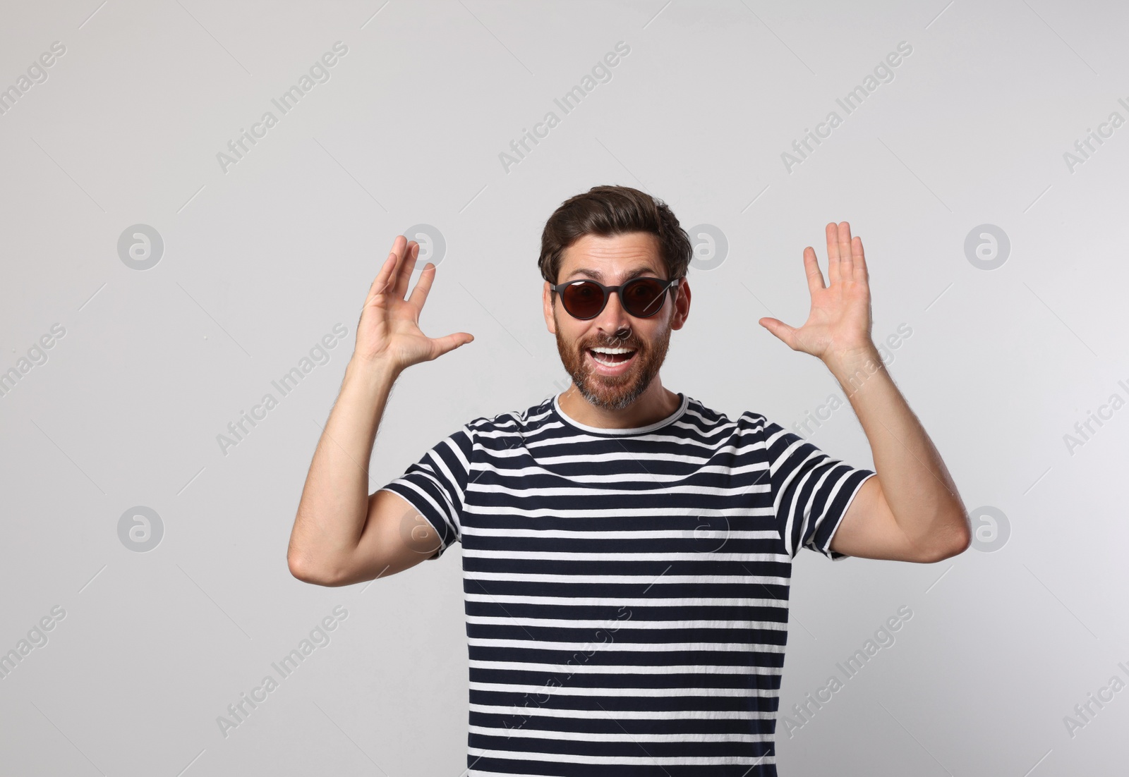 Photo of Portrait of excited bearded man with stylish sunglasses on grey background