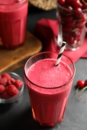 Photo of Tasty fresh milk shake with straw on black table, closeup