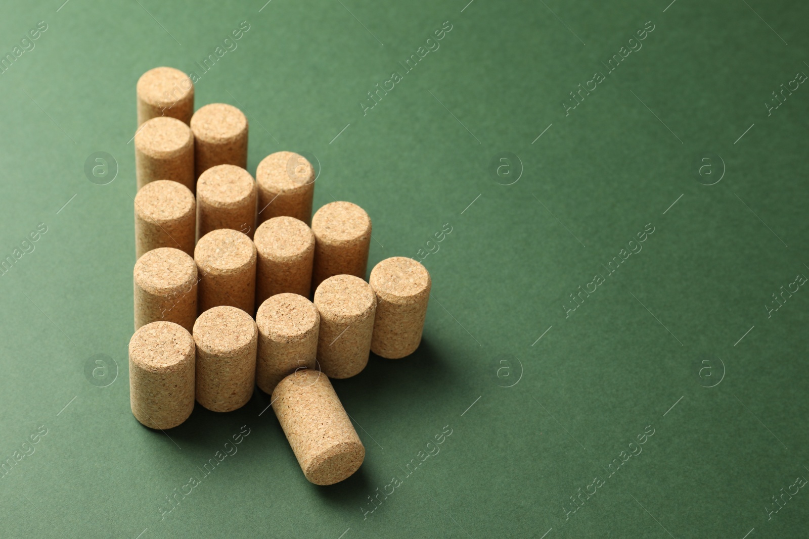 Photo of Christmas tree made of wine corks on green background. Space for text