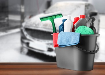 Image of Bucket with cleaning supplies on wooden surface at car wash. Space for text