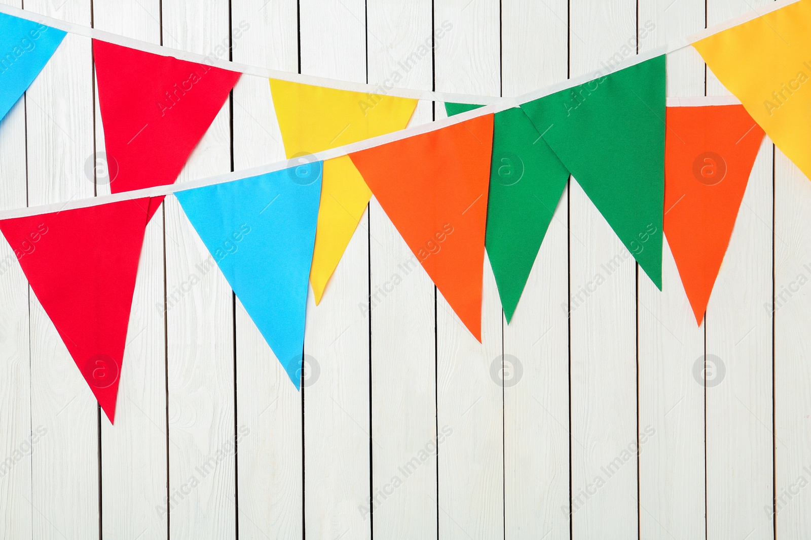 Photo of Buntings with colorful triangular flags on white wooden background